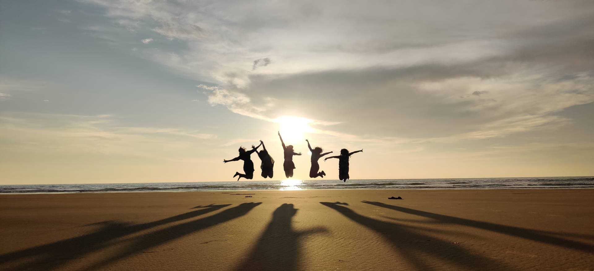 Travellers jumping on a Gokarna beach at sunset